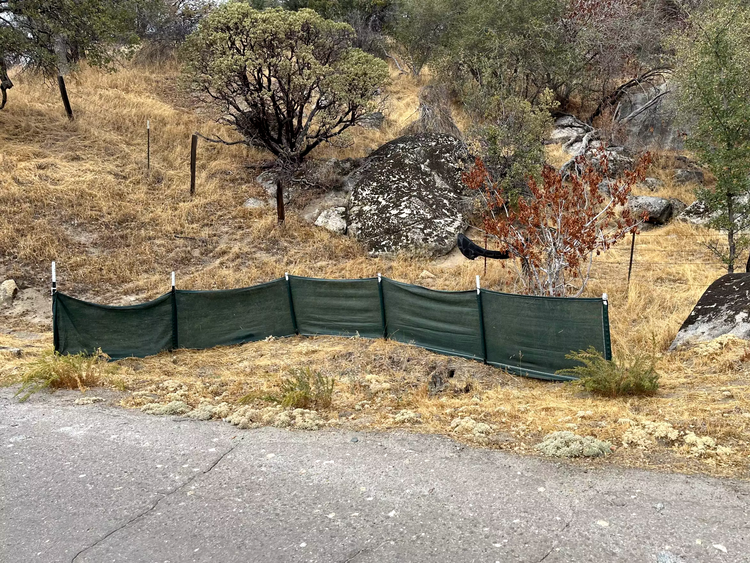 Green weather barrier by a hill and pavement