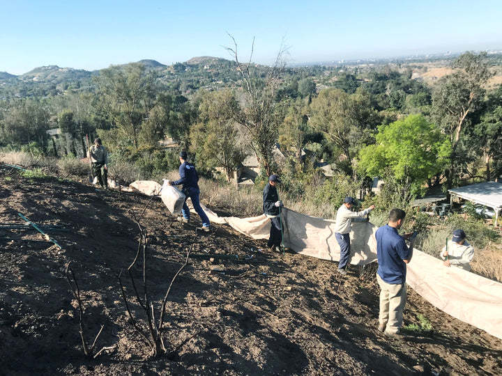 People doing a weather barrier hillside installation