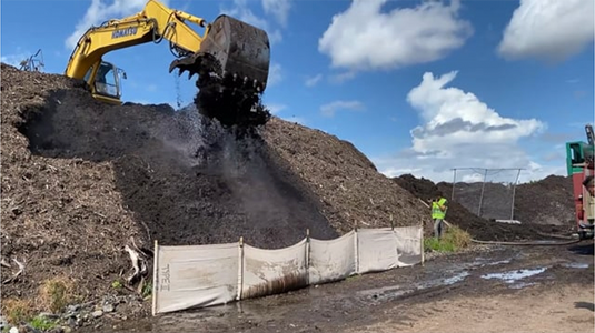 Excavator digging up dirt next to a protection barrier