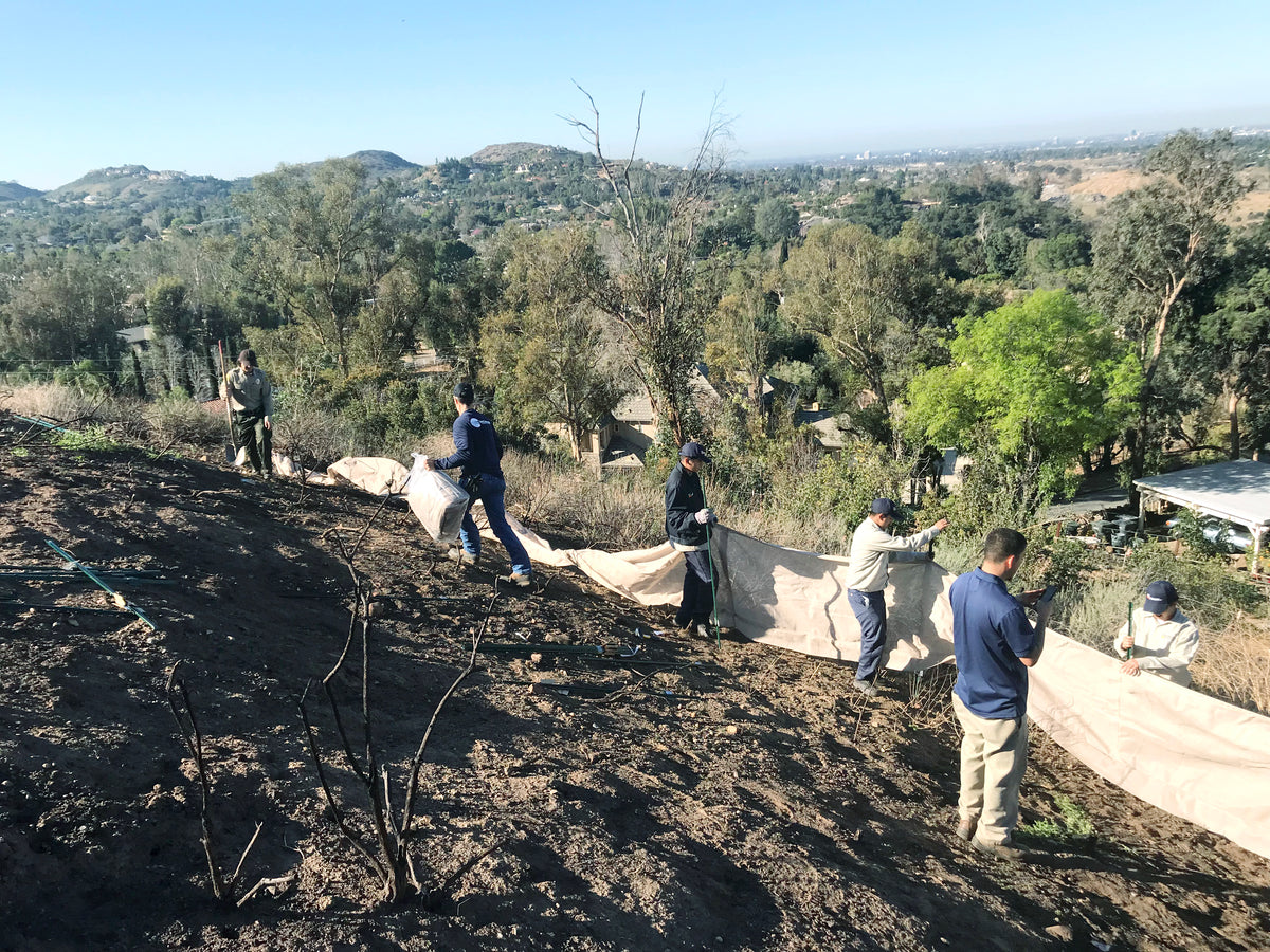 People doing a weather barrier hillside installation