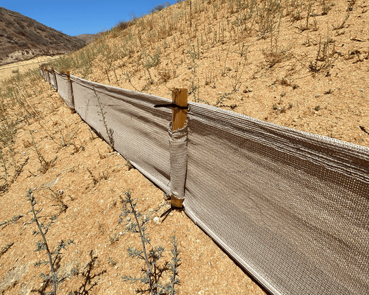 Weather barrier held up by posts in the desert